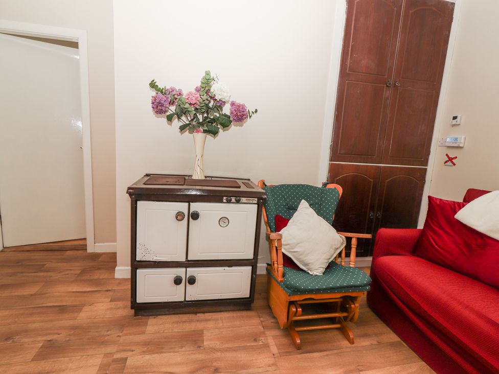 A living room with a cabinet, rocking chair, and sofa at Kate's Cottage
