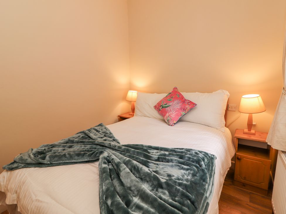 A bedroom with a bed and nightstands at Kate's Cottage