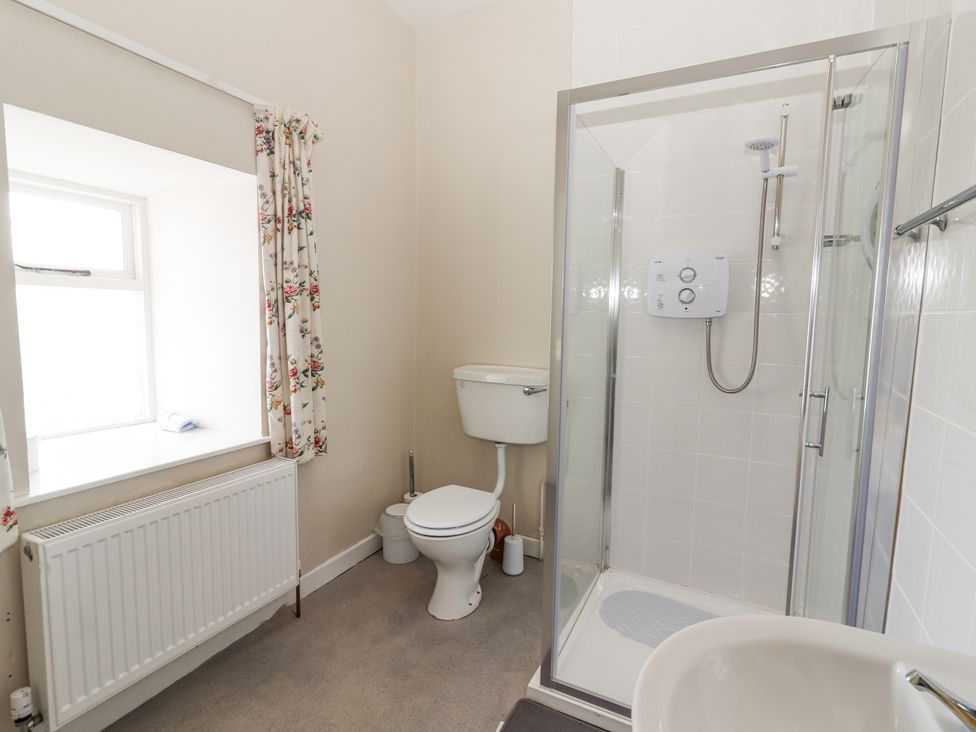 A bathroom featuring a shower, toilet, and window at Kate's Cottage