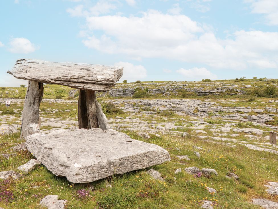 A stone table supported by pillars in a grassy landscape at Kate's Cottage