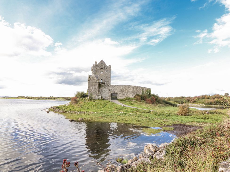 A castle near water with a path and grass at Kate's Cottage