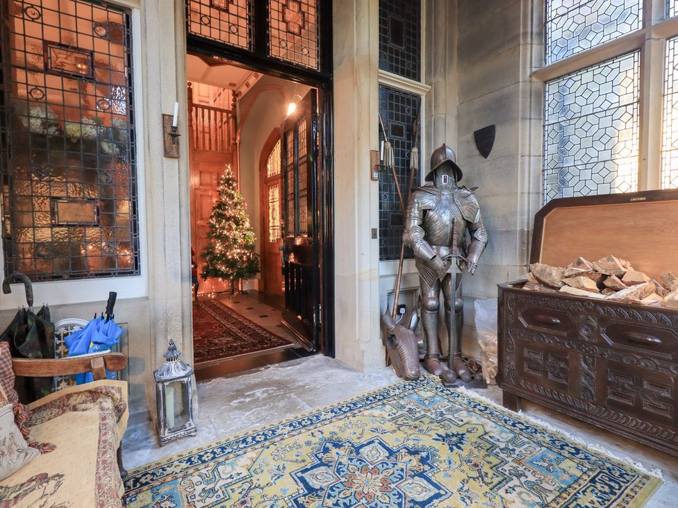 An entrance hall with a christmas tree and suit of armour at Summerlands Hall Apartment