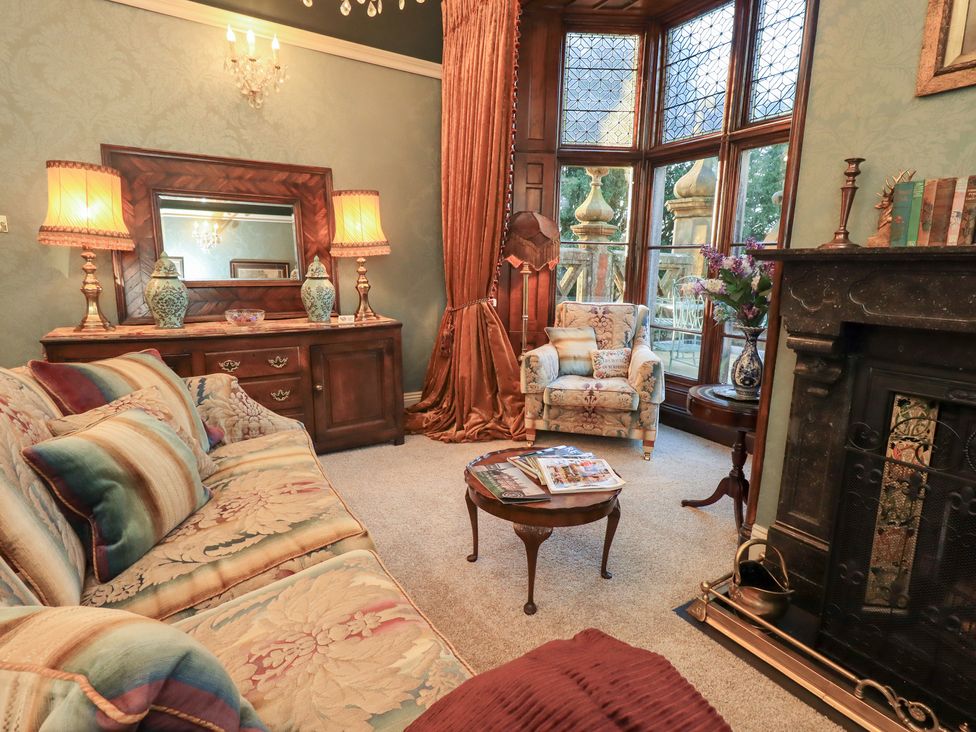 A living room with a sofa, armchair, and fireplace at Summerlands Hall Apartment