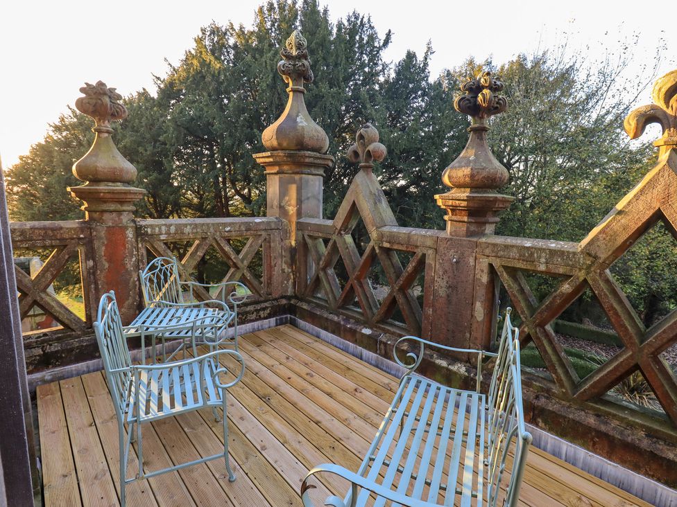 An outdoor terrace with seating and decorative pillars at Summerlands Hall Apartment