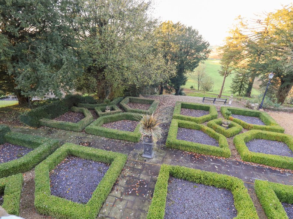 A garden with hedges and gravel pathways at Summerlands Hall Apartment