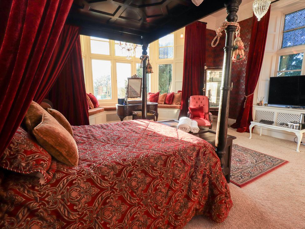 A bedroom with a four-poster bed and seating area at Summerlands Hall Apartment