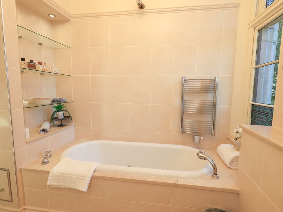 A bathroom with a bathtub and shelving for bath accessories at Summerlands Hall Apartment