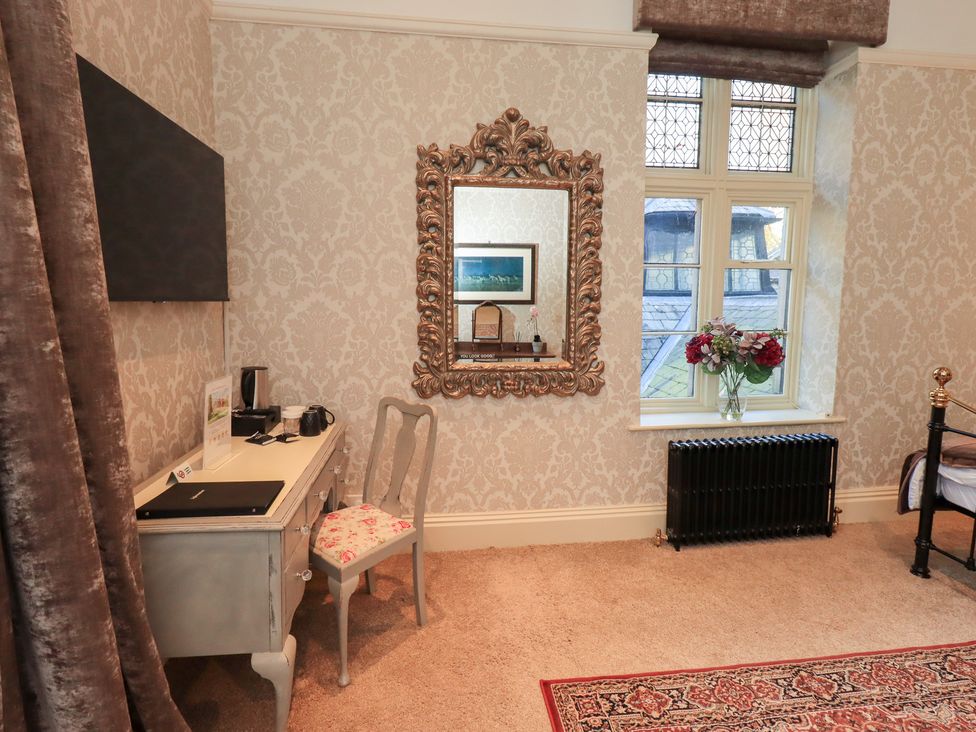 A bedroom with a desk, chair, mirror, television, and radiator at Summerlands Hall Apartment