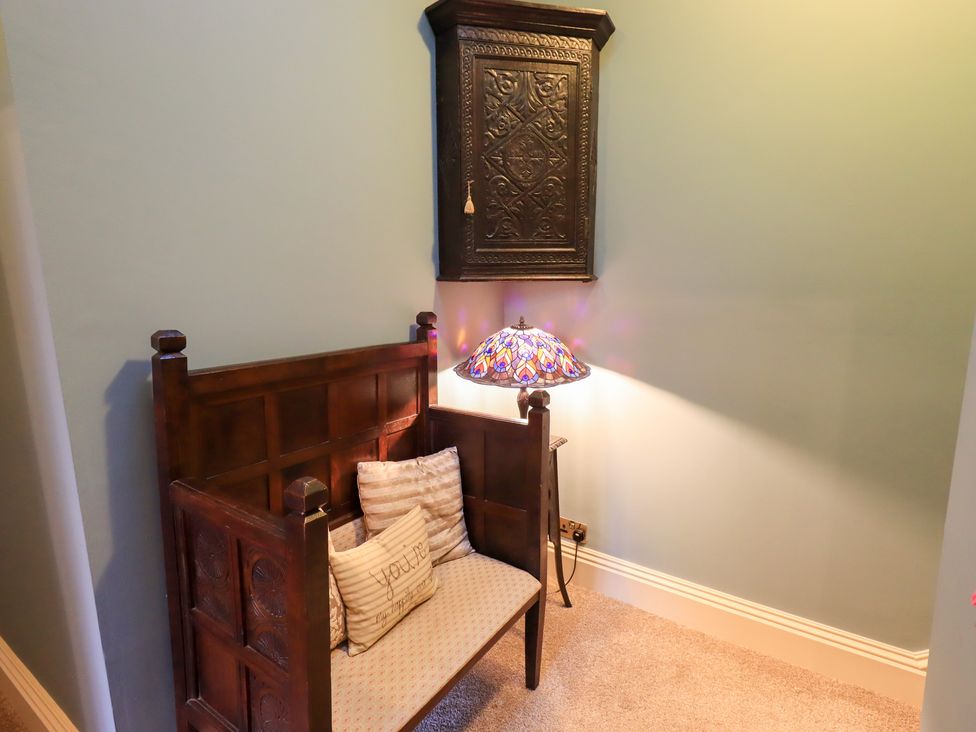 A small seating area with a bench and decorative lamp at Summerlands Hall Apartment
