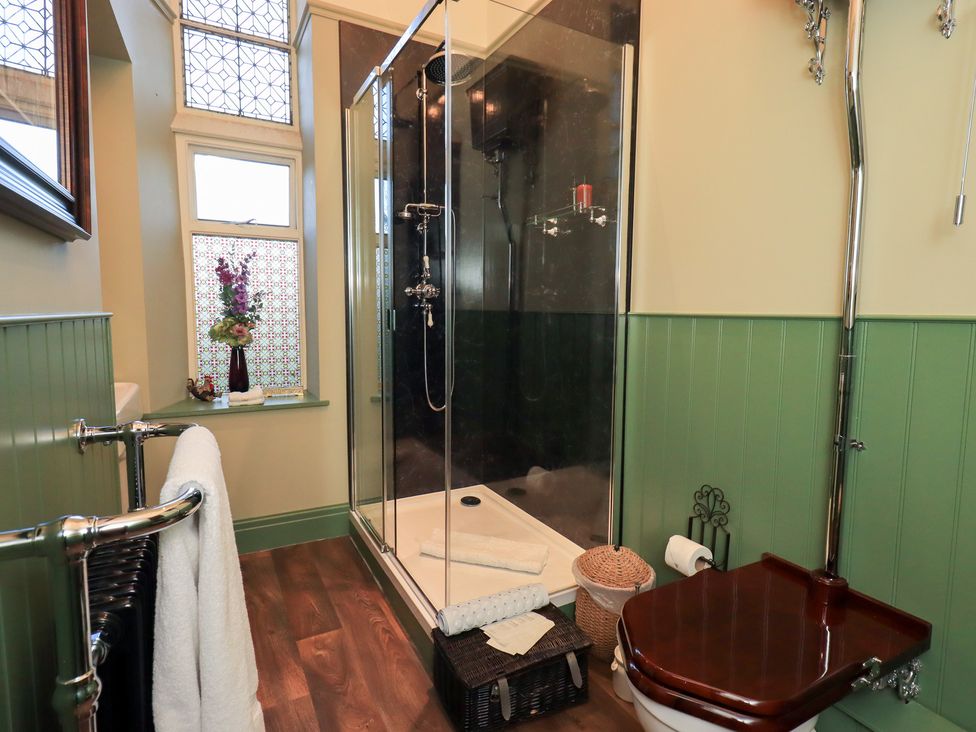 A bathroom with a shower, toilet, and towel rail at Summerlands Hall Apartment 
