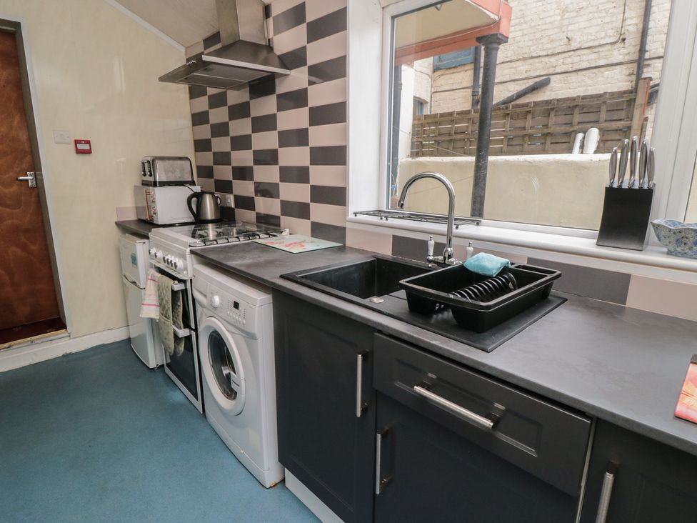 A kitchen with stove, sink, kettle, and washing machine at 170 Victoria Road