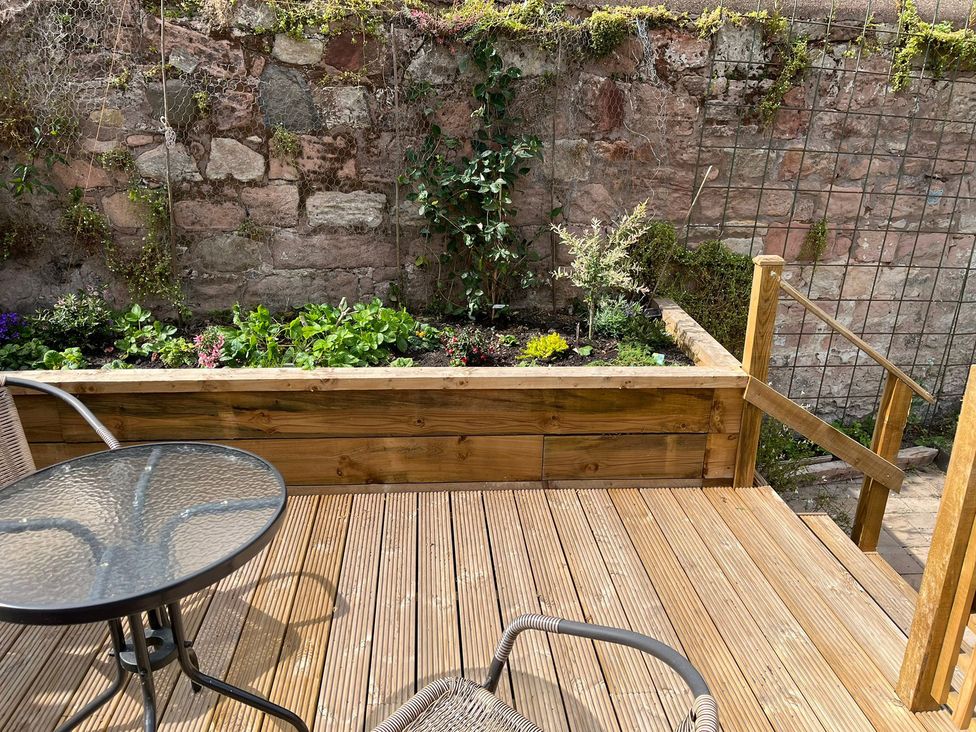 A garden with decking and a table and chair at Secret Garden in Berwick-Upon-Tweed