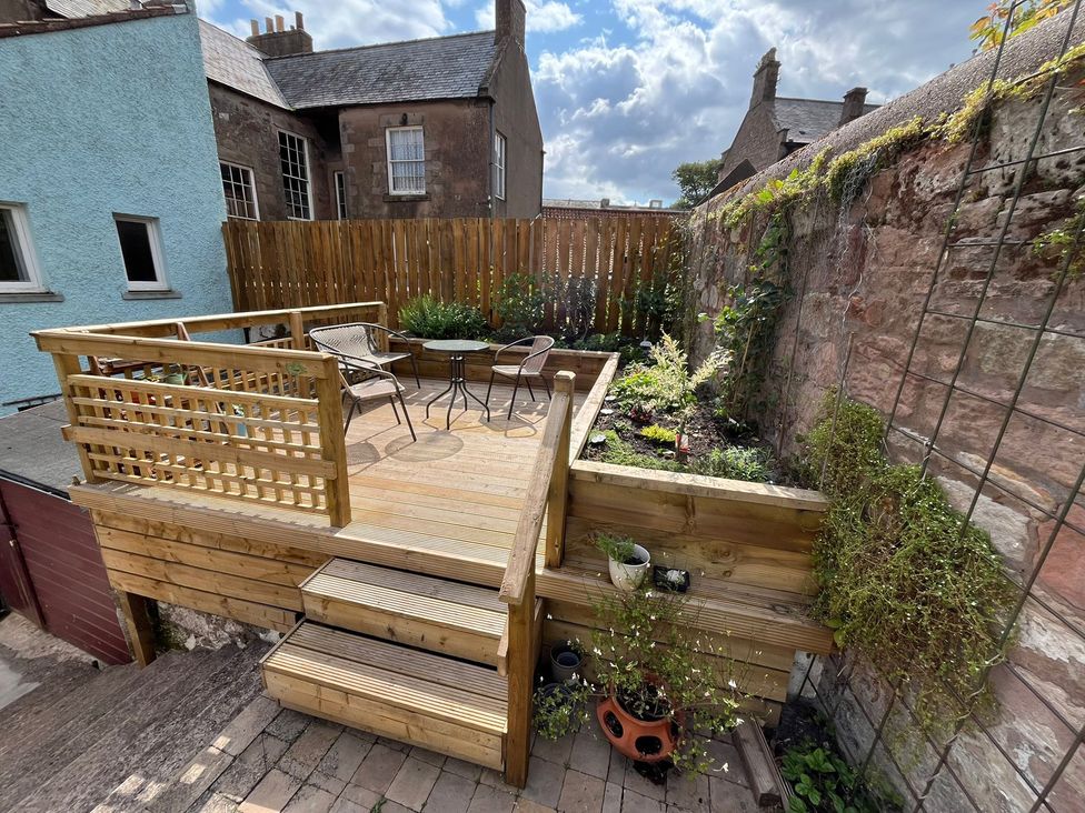 A garden with wooden decking and seating area at Secret Garden in Berwick-Upon-Tweed