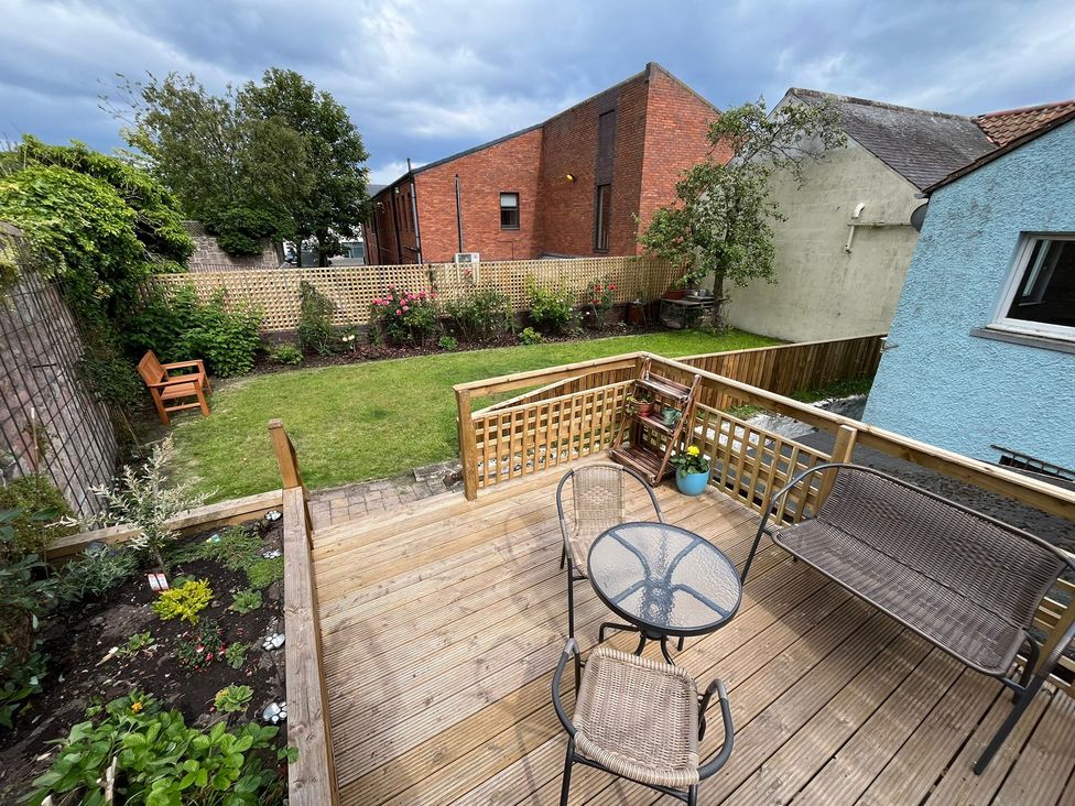 A garden with decking, table, chairs, and plants at Secret Garden in Berwick-Upon-Tweed