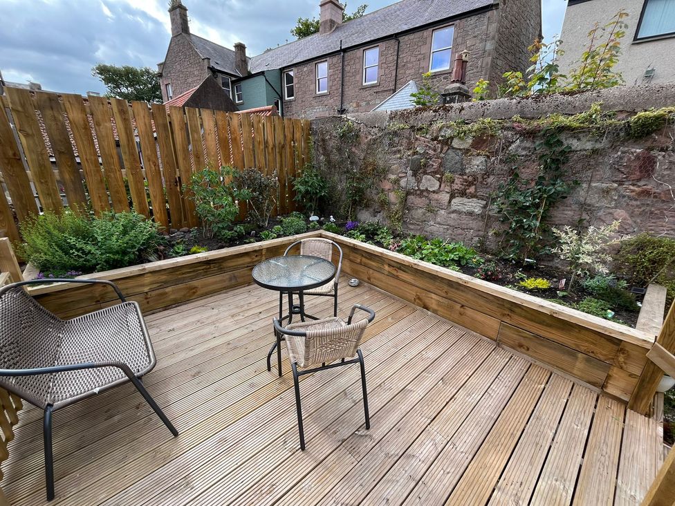 A garden with a wooden deck and outdoor furniture at Secret Garden in Berwick-Upon-Tweed