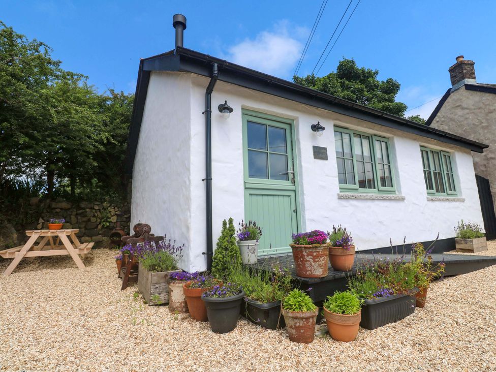 An outdoor area with a cottage surrounded by plants and a table at Lavender Cottage