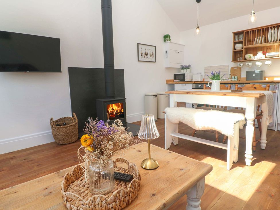 A living room with a wood stove and a table at Lavender Cottage