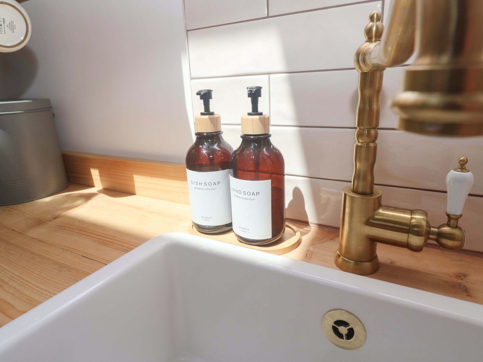 A sink with dish soap and hand soap bottles at Lavender Cottage 