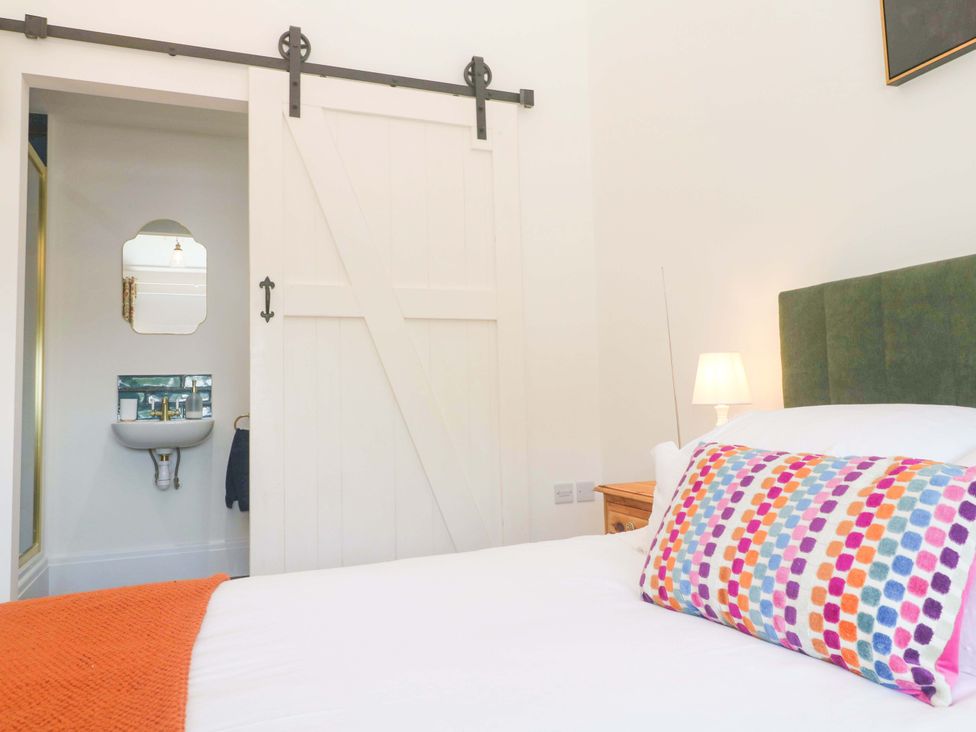 A bedroom with a bed and a sliding door leading to a small wash area at Lavender Cottage