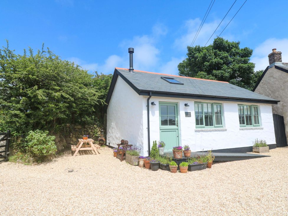 A cottage with a door and windows surrounded by plants and gravel at Lavender Cottage
