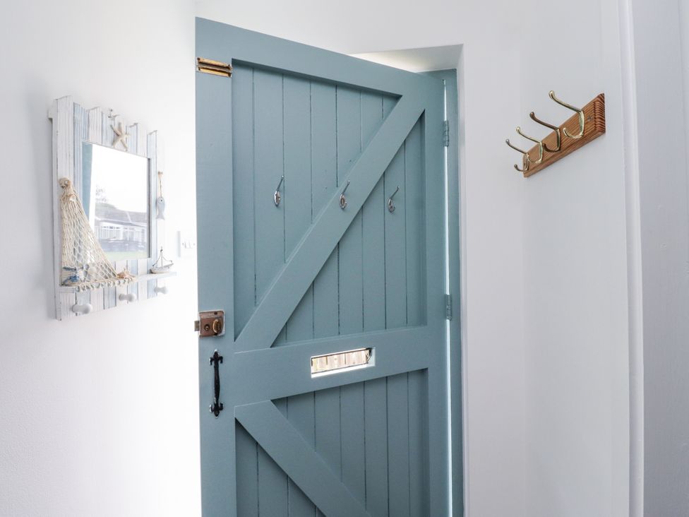 An entryway with a blue door, mirror, and hooks at 51 Longstone Park