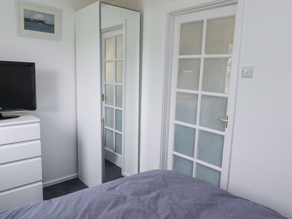 A bedroom with a television, dresser, and mirror at 51 Longstone Park