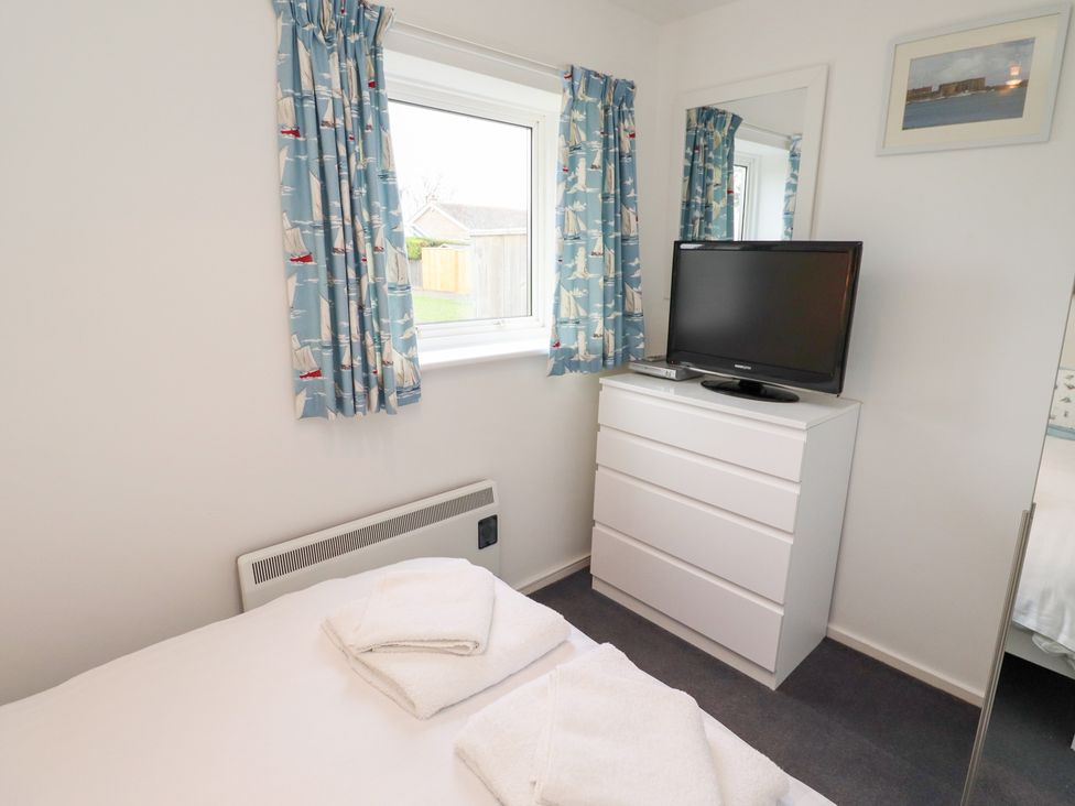 A bedroom with a bed, television, and dresser at 51 Longstone Park in Beadnell