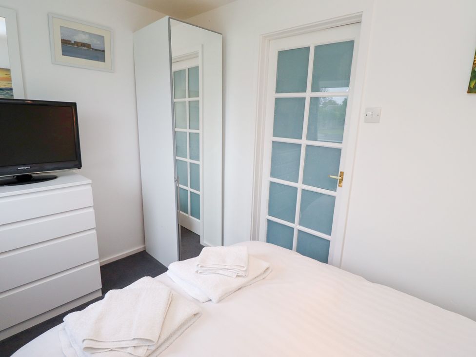 A bedroom with a television and a mirror at 51 Longstone Park in Beadnell