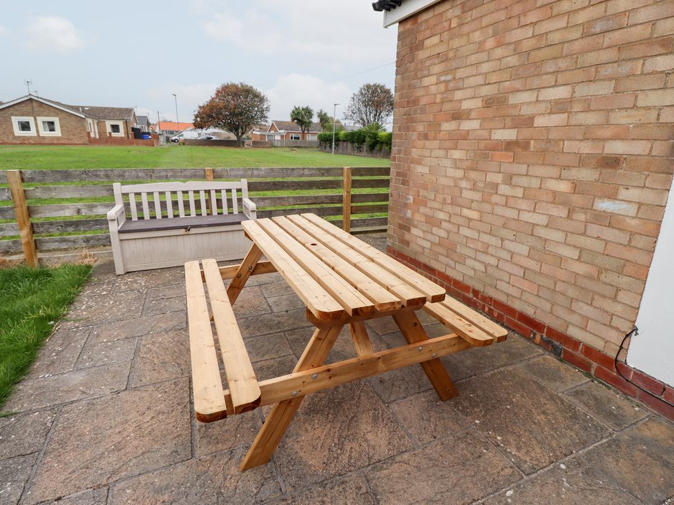 A wooden picnic table and bench in an outdoor area at 51 Longstone Park Beadnell