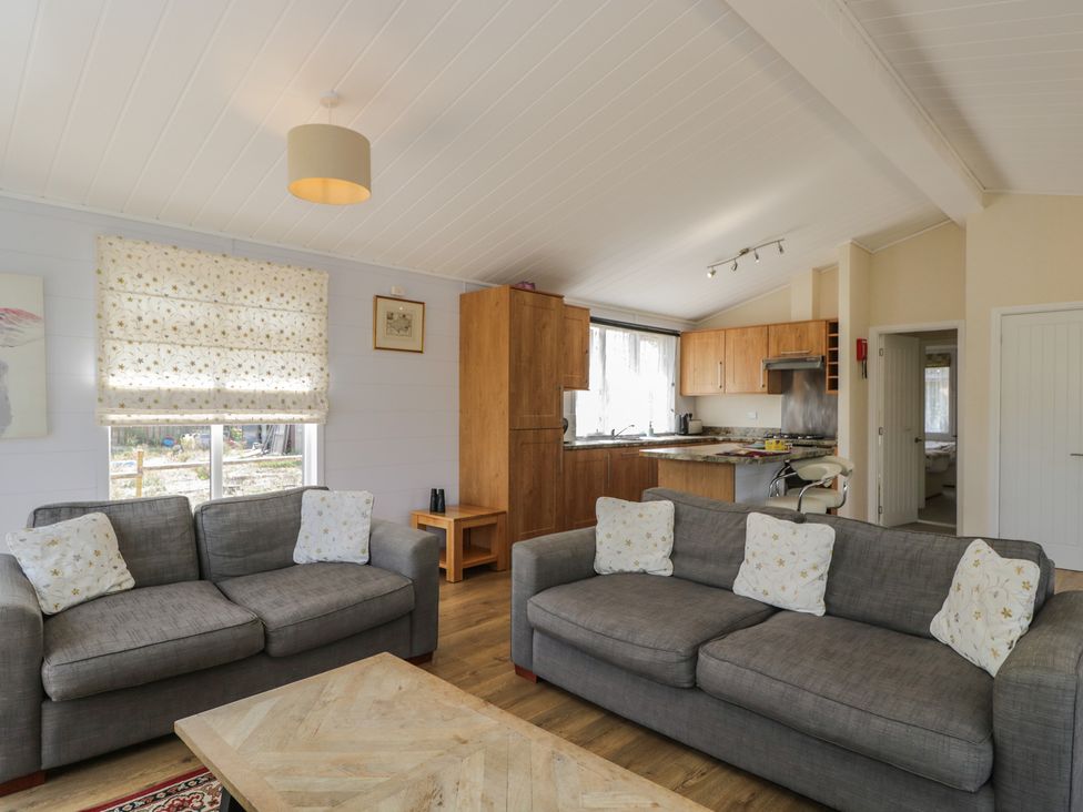 A living room with sofas and a kitchen area at The Buckland in Pentridge near Sixpenny Handley