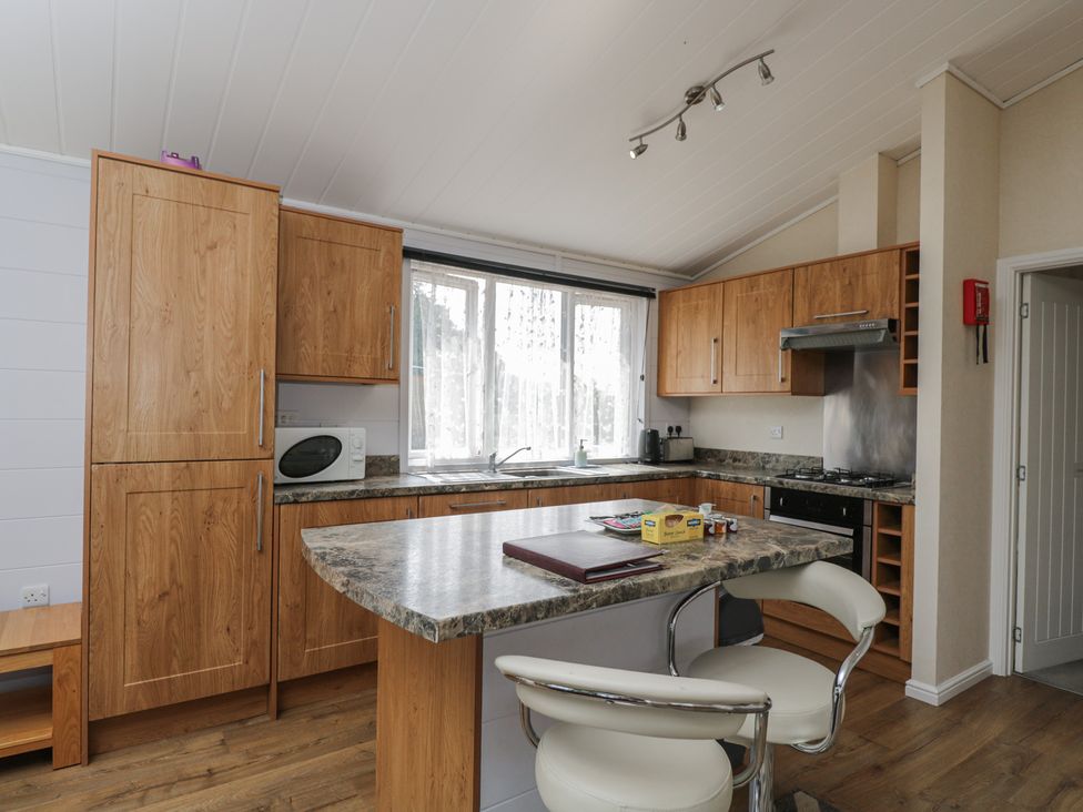 A kitchen with wooden cabinets and a microwave at The Buckland in Pentridge near Sixpenny Handley