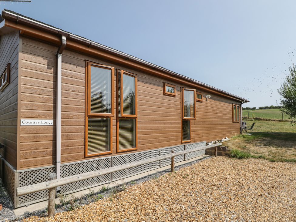 A wooden lodge with multiple windows at Whitey Top Country Lodge in Pentridge near Sixpenny Handley