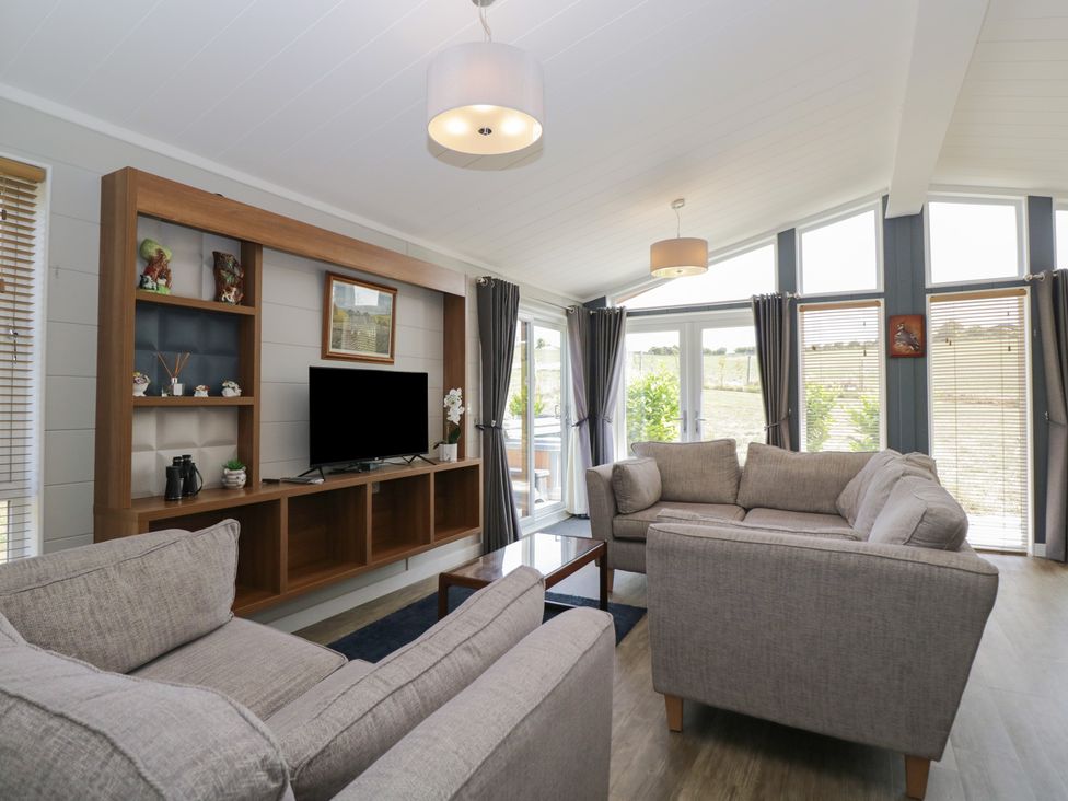A living room with a television on a shelf at Whitey Top Country Lodge in Pentridge near Sixpenny Handley