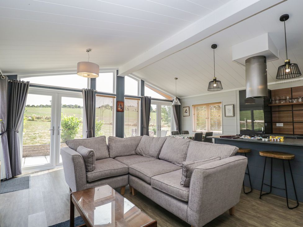 A living room with a sofa and kitchen area at Whitey Top Country Lodge Pentridge near Sixpenny Handley