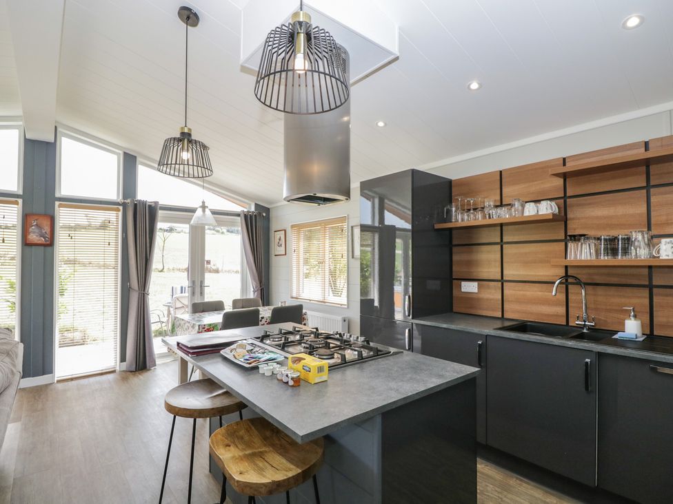 A kitchen with a stove and bar stools at Whitey Top Country Lodge Pentridge near Sixpenny Handley