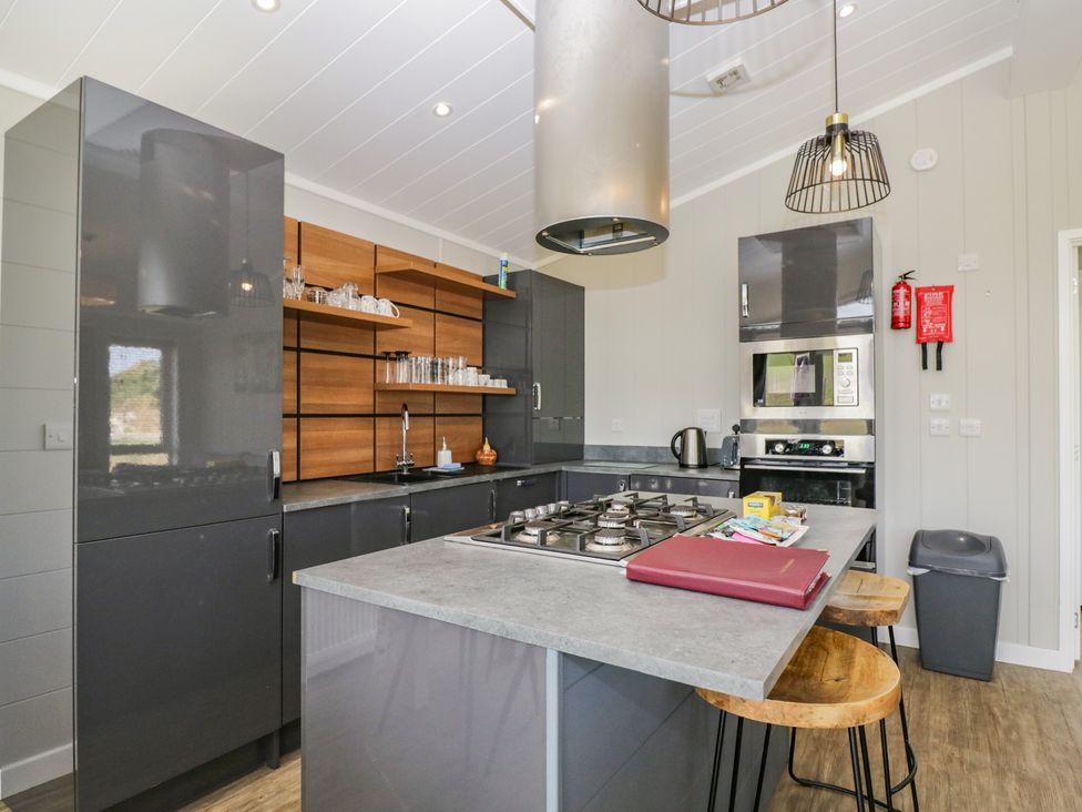 A kitchen with cabinets, stove and bar stools at Whitey Top Country Lodge Pentridge near Sixpenny Handley