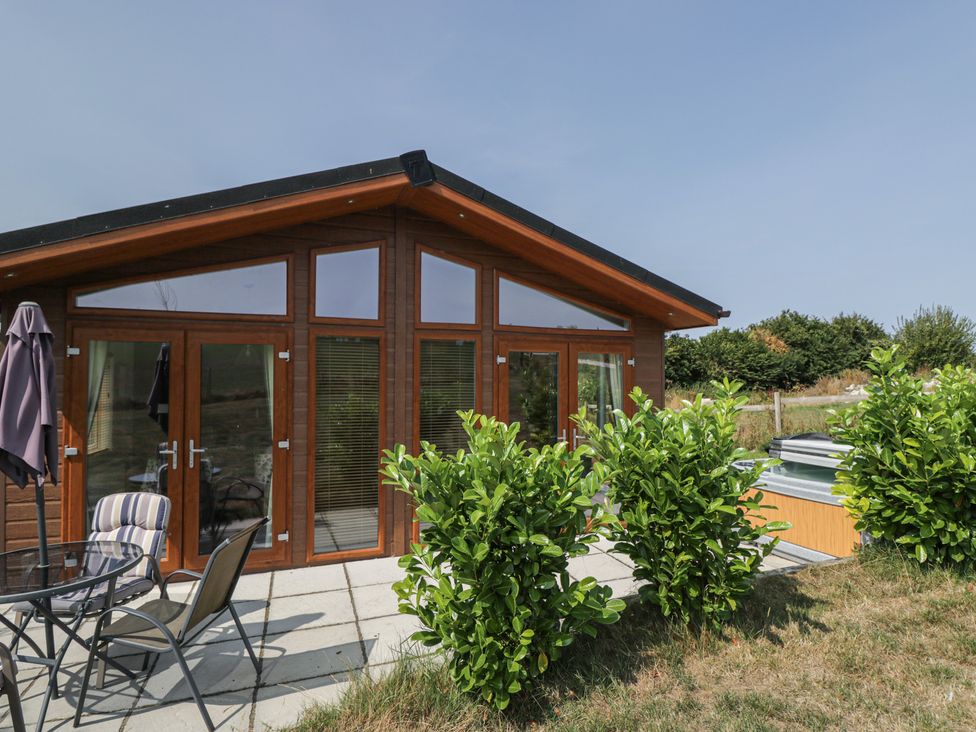A cabin with patio furniture and bushes at Whitey Top Country Lodge Pentridge near Sixpenny Handley