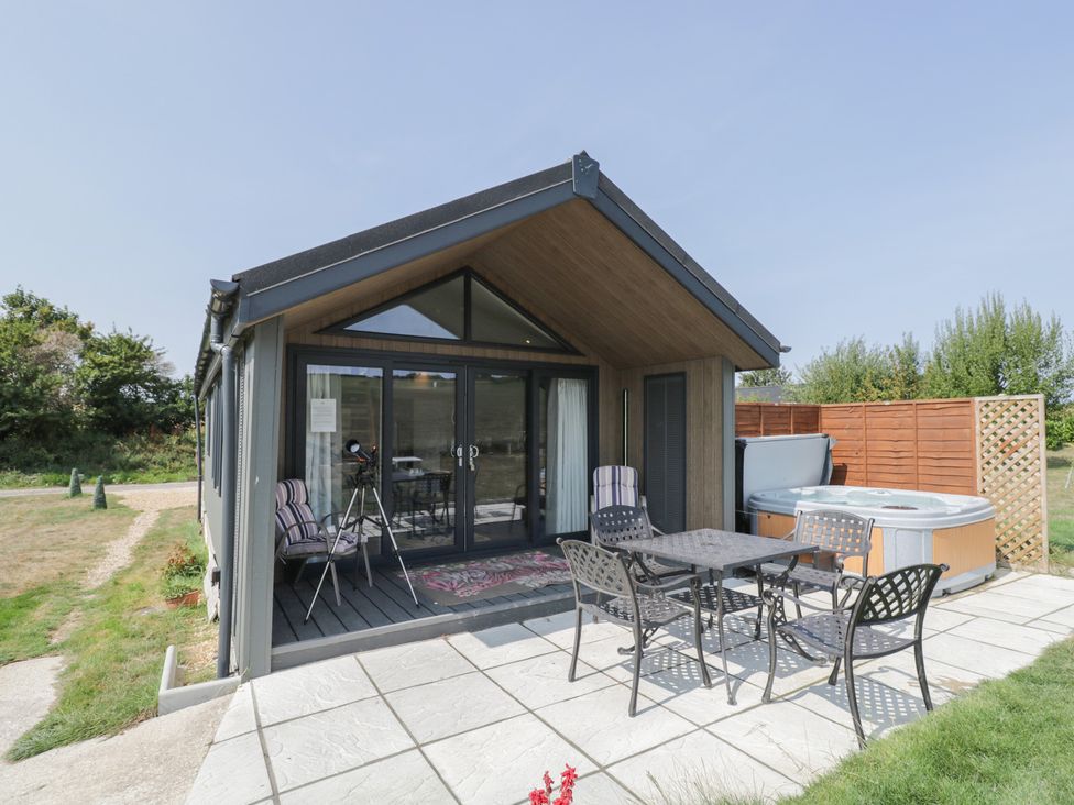 An outdoor area with a table and chairs near a hot tub at Cranborne Chase Stargazer in Pentridge near Sixpenny Handley