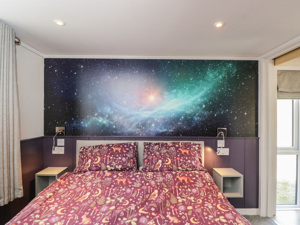 A bedroom with a bed and cosmic wall decor at Cranborne Chase Stargazer in Pentridge near Sixpenny Handley