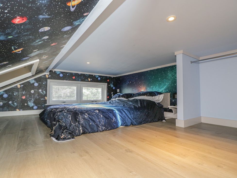 A bedroom with a bed and space-themed wallpaper at Cranborne Chase Stargazer in Pentridge near Sixpenny Handley