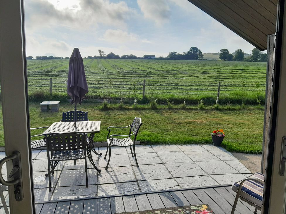 A patio area with table and chairs overlooking a field at Cranborne Chase Stargazer Pentridge near Sixpenny Handley
