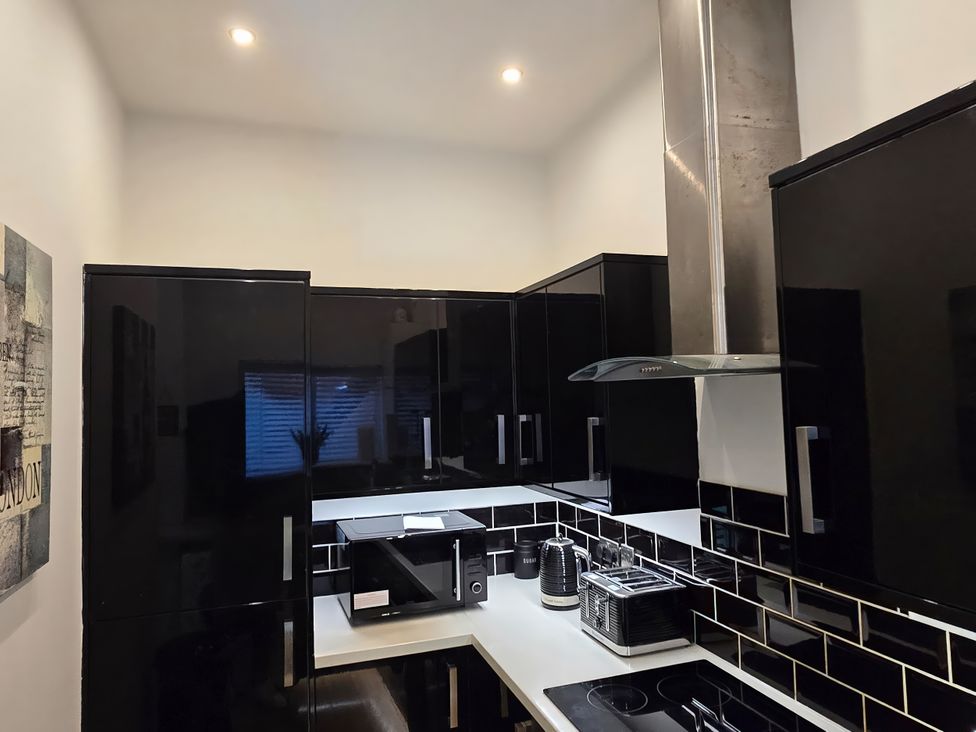 A kitchen with cabinets, microwave, and kettle at 2 Fern Avenue in Prestatyn