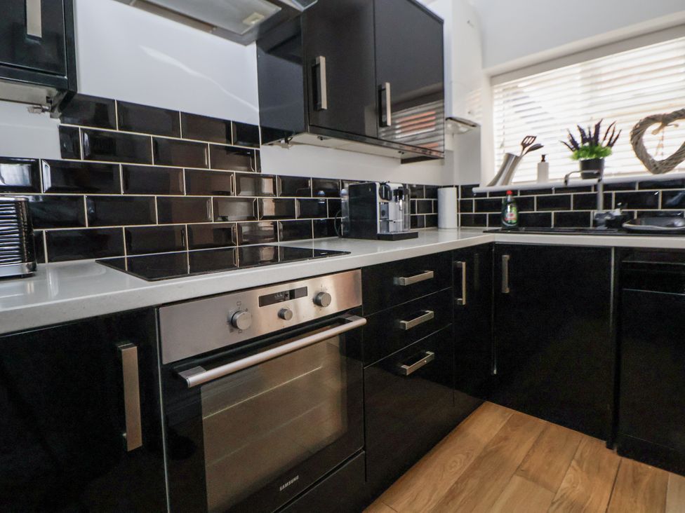 A kitchen with modern appliances and black cabinetry at No 2 Emporium Apartments in Prestatyn