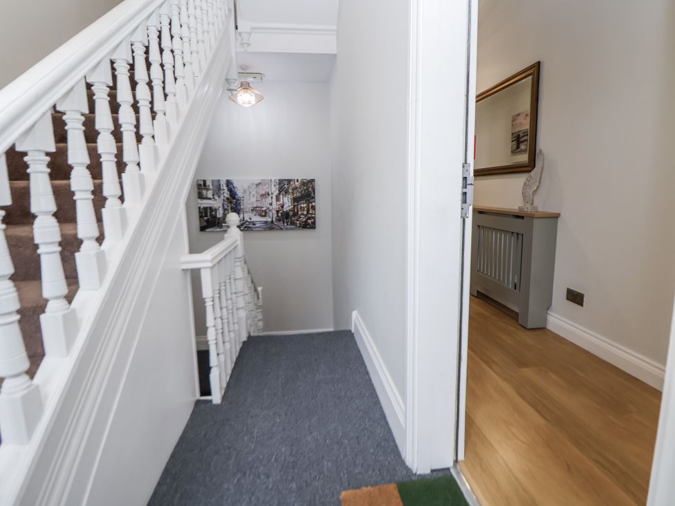 A hallway with a staircase and a console table at No 2 Emporium Apartments in Prestatyn