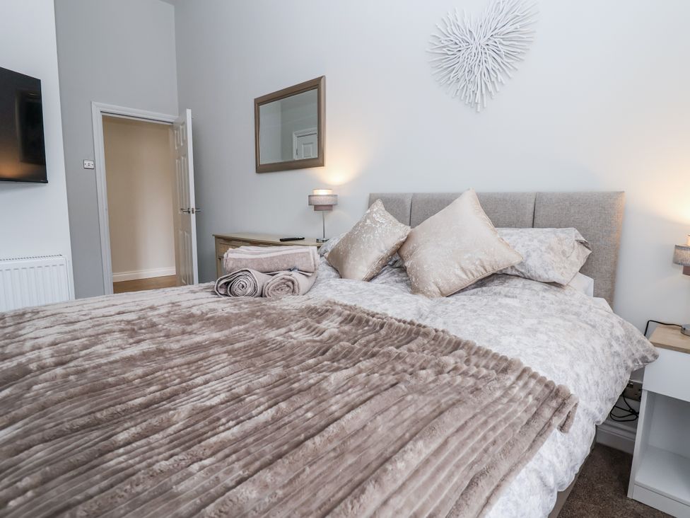 A bedroom with a bed and a mirror at No 2 Emporium Apartments in Prestatyn