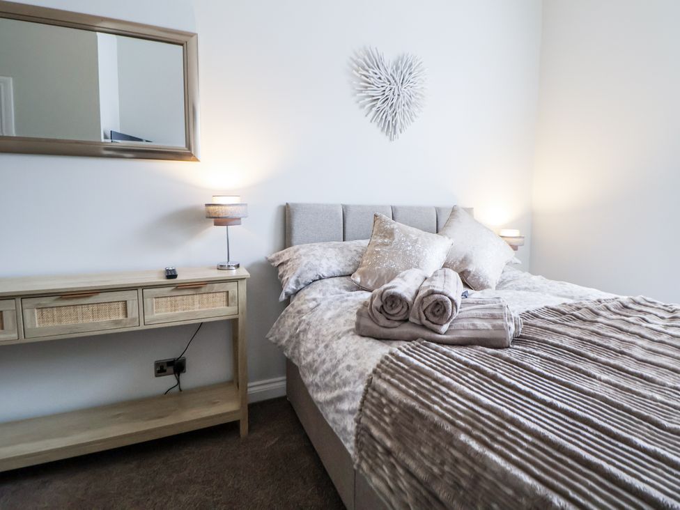 A bedroom with a bed and a console table at No 2 Emporium Apartments in Prestatyn