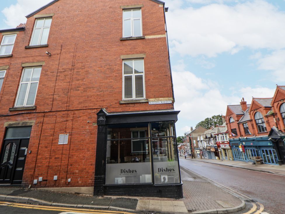 A brick building with a storefront and street view at No 2 Emporium Apartments in Prestatyn