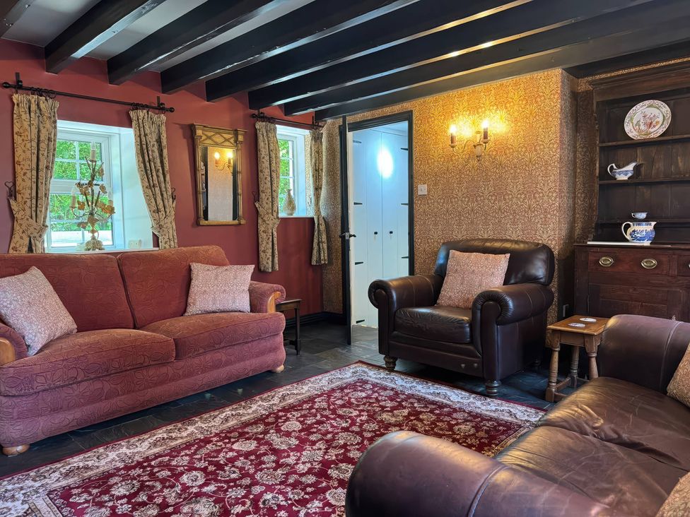 A living room with sofas and a rug at St. James Cottage in Liskeard
