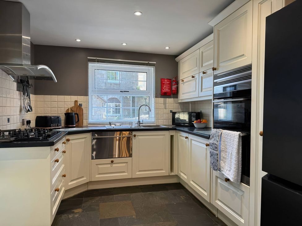 A kitchen with appliances and a window at St. James Cottage in Liskeard