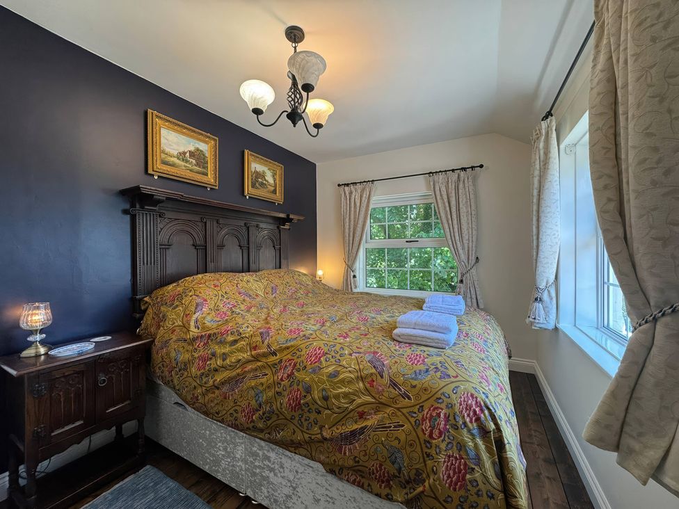 A bedroom with a large bed and paintings on the wall at St. James Cottage in Liskeard